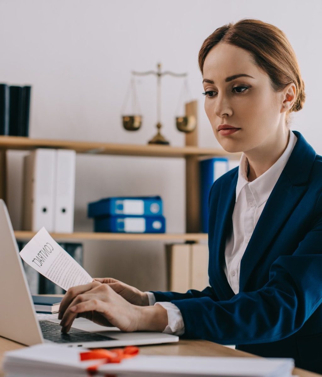 focused-female-lawyer-working-on-laptop-at-workplace-in-office-e1639537095135